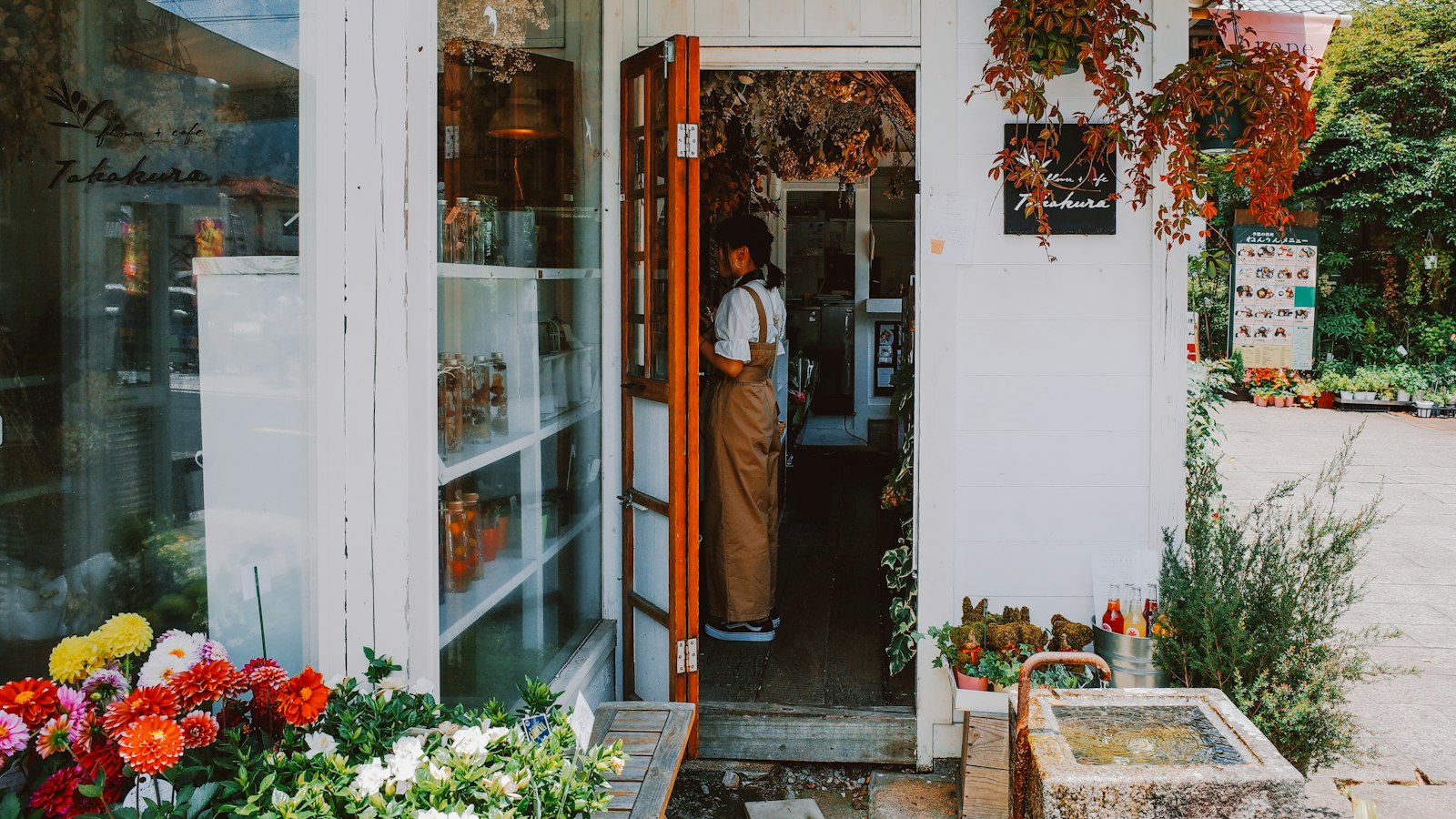 Commerçante sur le pas de la porte de sa boutique de fleurs
